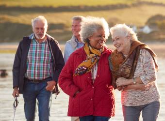 Senior vrienden die een strandwandeling maken tijdens een op maat gemaakte verjaardagstour